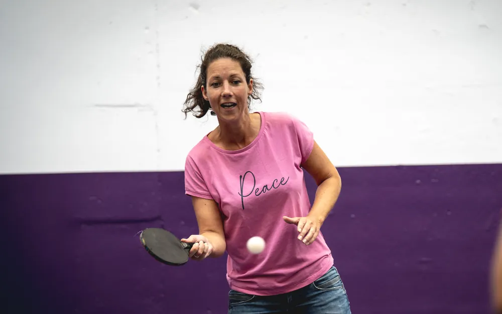 Spielerin im pinken Shirt spielt lächelnd eine Vorhand
