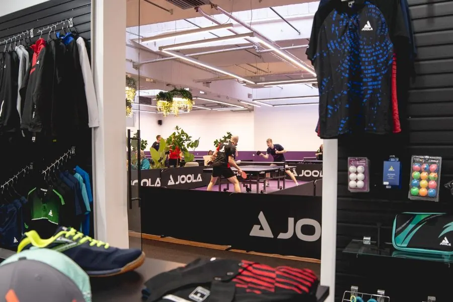 View from the shop past shirts and shoes into the hall, where two players are at a table